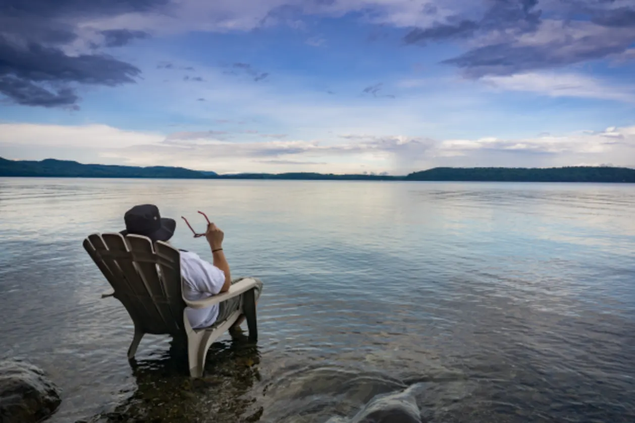boost well-being when you travel man sitting in adirondack chair on beach